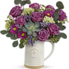 Purple roses and mixed flowers arranged in a white ceramic pitcher