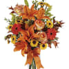 Orange lilies and mixed flowers in a clear glass vase