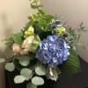 Bouquet of blue hydrangea, pale roses, and thistle in a vase