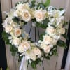 Heart-shaped floral wreath of white roses and lilies on a stand