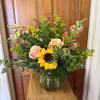 Mixed bouquet with sunflowers, blush roses, and yellow filler in a glass vase