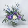 Mixed bouquet in a clear glass vase with blue, purple, and white flowers