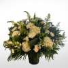 White floral arrangement in a black vase with mixed blooms and greenery