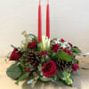 Red roses and pinecones arranged with two tall red candles.