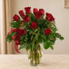 Red roses arranged in a clear glass vase with a red ribbon