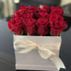 Red roses arranged in a white box tied with a cream ribbon