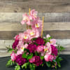 Pink orchids and roses arranged with magenta blooms in a low bouquet