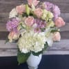 Pink roses, white lilies, and lavender daisies in a white vase