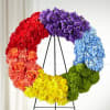 Circular floral wreath in rainbow colors on a black stand