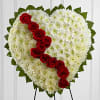 Heart-shaped floral tribute with white flowers and red roses on an easel