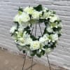 White floral wreath on a black stand