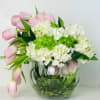 Pink tulips and white hydrangeas in a round glass vase