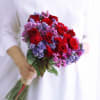 Handheld bouquet of red roses with purple and pink filler flowers