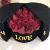 Red roses in a black hatbox with gold "LOVE" lettering
