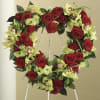 Heart-shaped wreath of red roses and green orchids on a stand