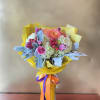 Bouquet of pink and white flowers in a clear glass vase with yellow wrap
