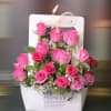 Pink roses arranged in a white gift bag with a ribbon handle