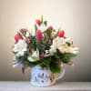 Bouquet of pink tulips and white lilies in a floral mug vase