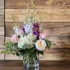 Pink and white roses with purple orchids in a glass vase
