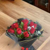 Bouquet of red roses wrapped in black paper with gold trim