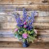 Purple and pink floral arrangement in a dark pedestal vase