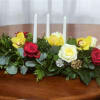 Low floral centerpiece with roses, orchids, and three white candles