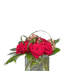 Red roses arranged in a clear glass cube vase with pink berries