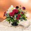 Red roses and white orchids in a black pedestal vase