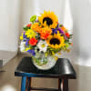 Mixed bouquet with sunflowers, orange roses, and daisies in a glass vase