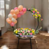Floral arrangement with pink and peach balloons on a circular frame