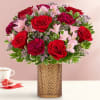Red roses and pink flowers arranged in a textured vase