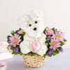 White flower teddy bear in a wicker basket with pink and purple daisies