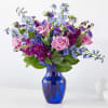 Pink roses and purple-blue flowers in a blue glass vase