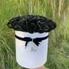 Black roses arranged in a white round box with a black ribbon