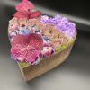 Heart-shaped flower arrangement with pink orchids, roses, and purple blooms in a wooden box