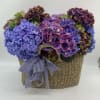Hydrangea arrangement in a woven basket with a striped ribbon