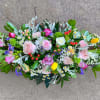 Low elongated arrangement of pink roses, yellow tulips, and mixed spring flowers