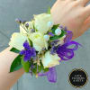 White rose wrist corsage with purple flowers, pearls, and ribbon on a person's arm