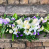 Low white lily and rose arrangement with purple and white daisies and ferns on stone steps