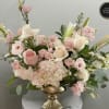 Low arrangement of pink and white roses, lilies, lisianthus and hydrangeas in a gold pedestal bowl