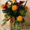 Mixed bouquet with orange roses, burgundy calla lilies, and yellow dahlias in a glass vase
