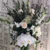 White floral arrangement with orchids and roses in a green vase