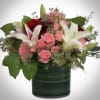 Pink and white roses with lilies in a dark green vase