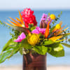 Tropical bouquet with bird of paradise, pink blooms, and yellow pincushion flowers in a vase