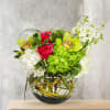 Bouquet of pink roses, green orchids, and white blooms in a glass vase