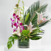 Tropical floral arrangement with orchids and lilies in a glass vase