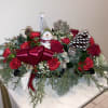Christmas floral centerpiece with red flowers, pinecones, and a snowman ornament