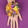 Orange and yellow floral wrist corsage on a hand