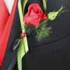Red rose boutonniere with green accents pinned to a black suit