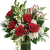 Red roses and white flowers in a green glass vase with candy canes